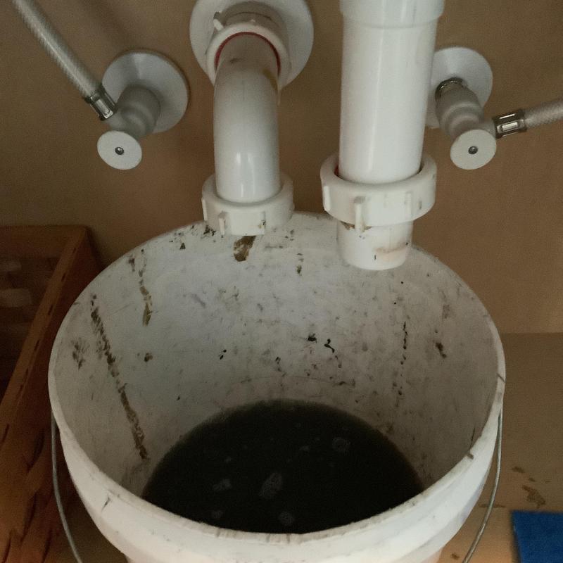 Bathroom sink drainpipe with dirty water in bucket Bathroom sink drainpipe with dirty water in bucket