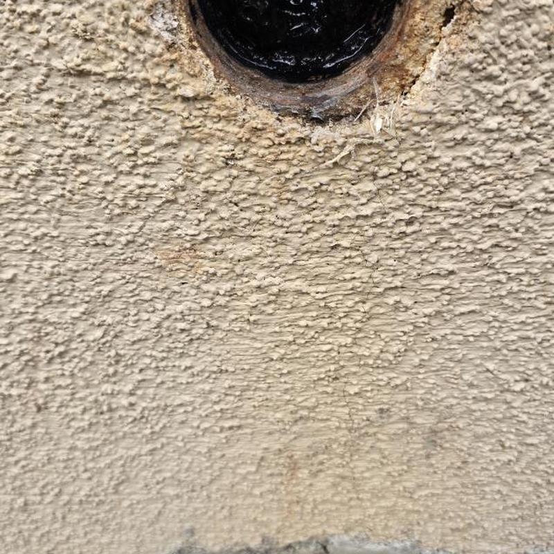 Drain clean-out pipe opening on textured wall