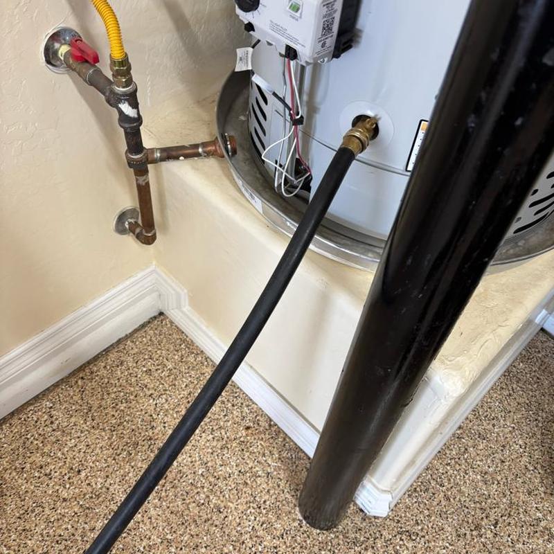 Water heater flushing with attached hose in garage corner