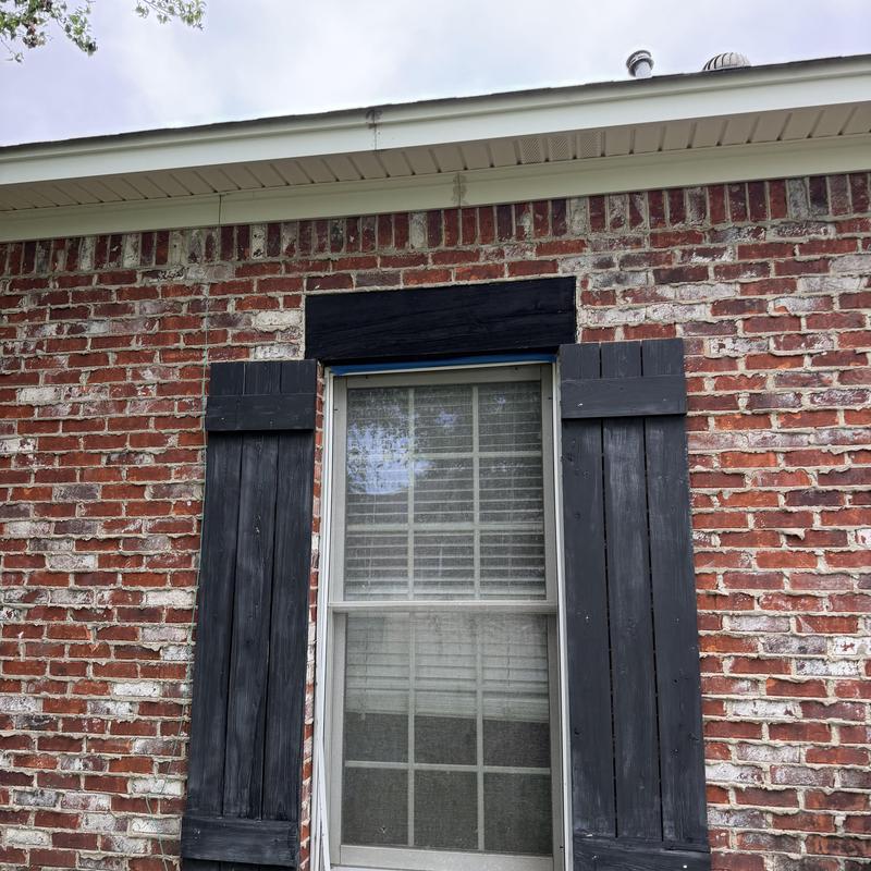 Window with black wooden shutters on brick wall