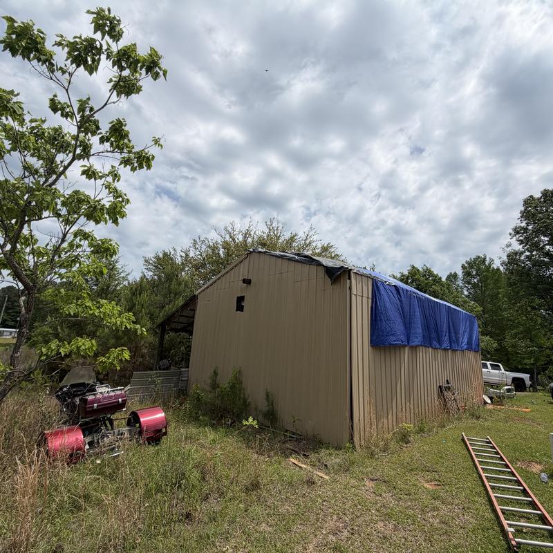 Metal barn roof with tarp covering after damage
