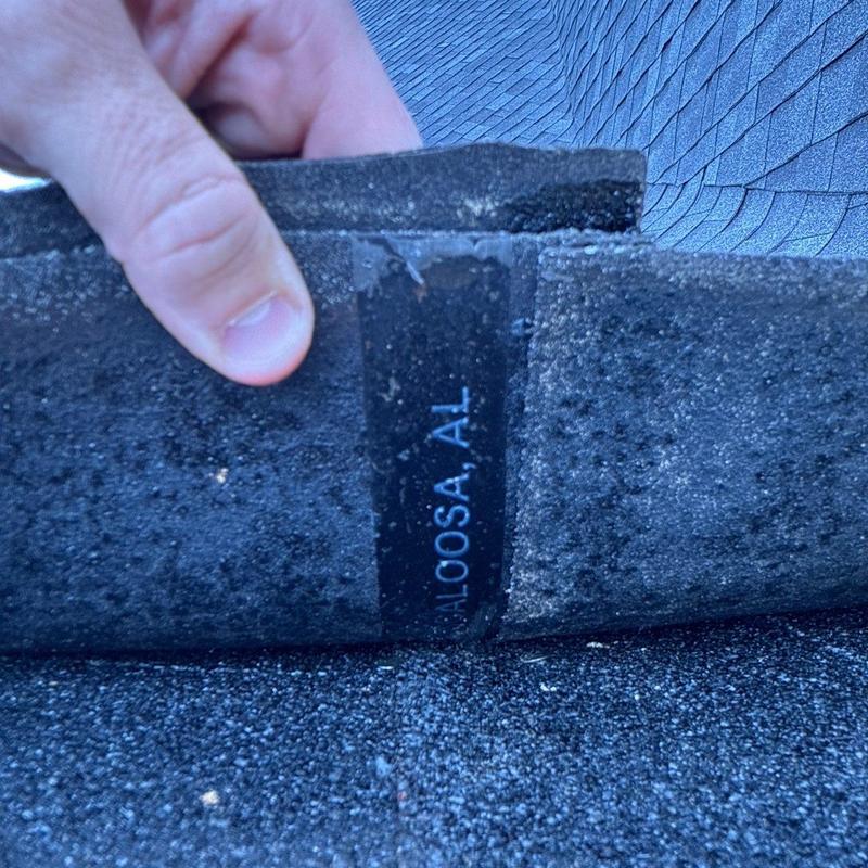 Roof shingles close-up showing hail damage and label