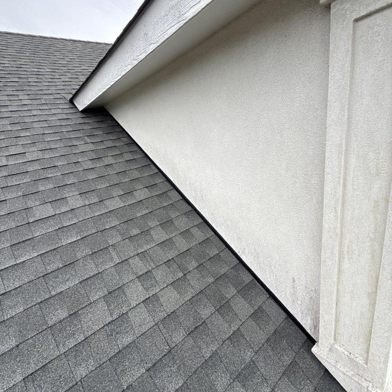 Asphalt shingle roof inspection near stucco wall