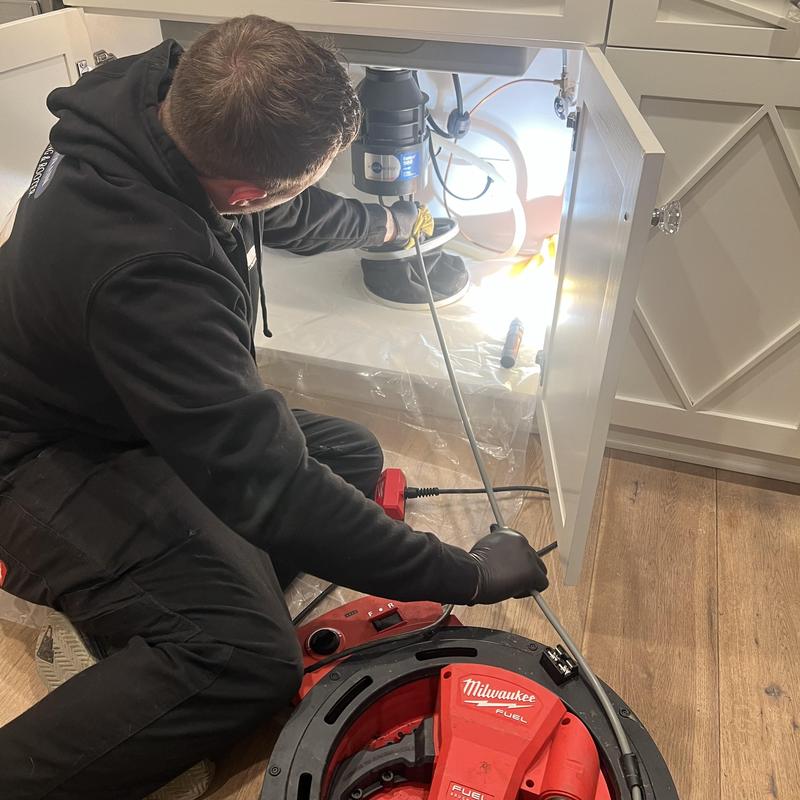 Kitchen drain line clog removal with plumbing snake