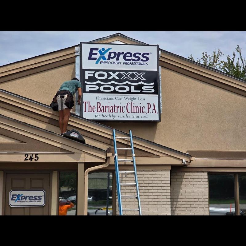 Commercial roof with ladder and worker repairing sign Commercial roof with ladder and worker repairing sign