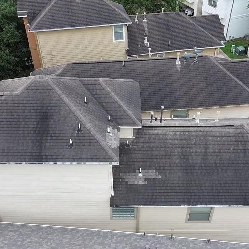 Asphalt shingle roof with damaged patches on townhouse