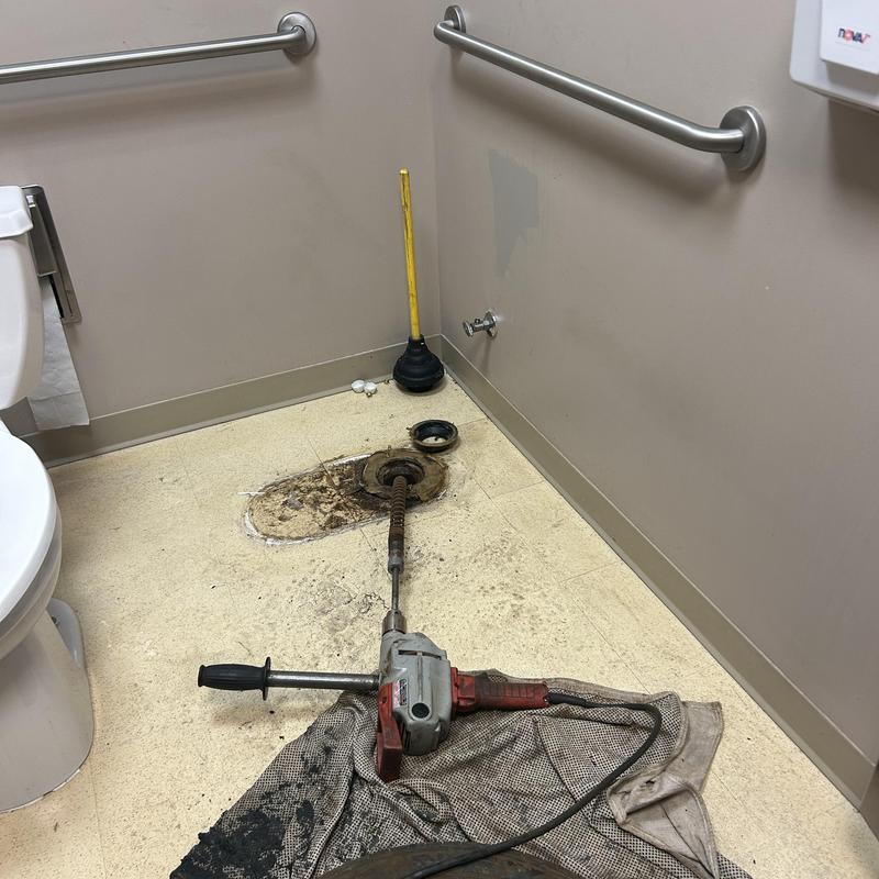 Main line drain auger tool in commercial restroom Main line drain auger tool in commercial restroom