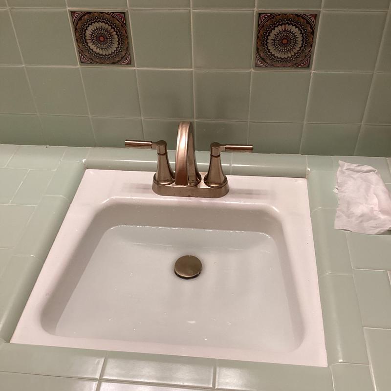 Gold Delta vanity faucet with tiled countertop