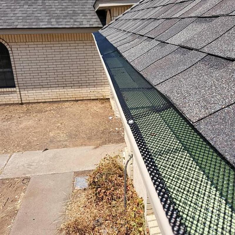 Seamless gutter with black mesh guard on roof edge