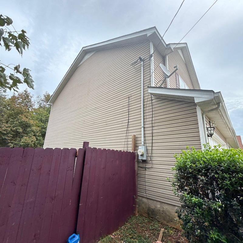 Vinyl siding exterior wall with utility meter and fence