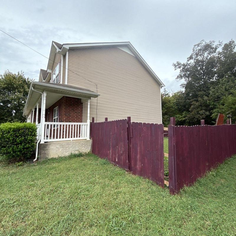 Wood fence gate with missing pickets near house siding