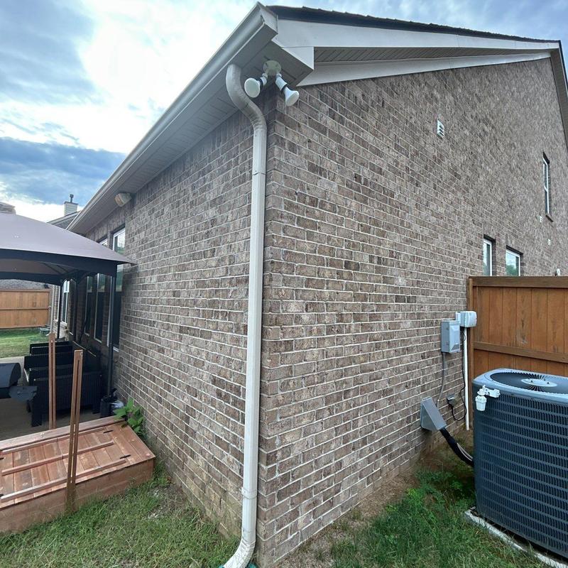 Air conditioner unit beside brick house exterior wall