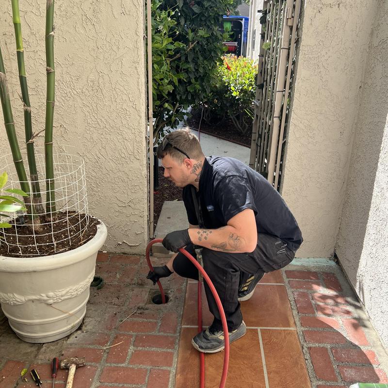 Storm drain hydro jetting with red hose outdoors Storm drain hydro jetting with red hose outdoors