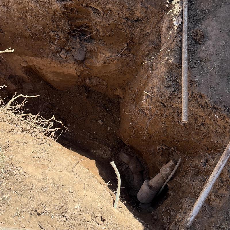 Sewer line excavation with visible pipe joints in trench