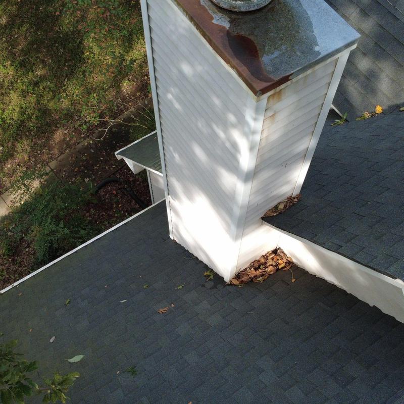 Roof shingles and chimney base with leaf debris