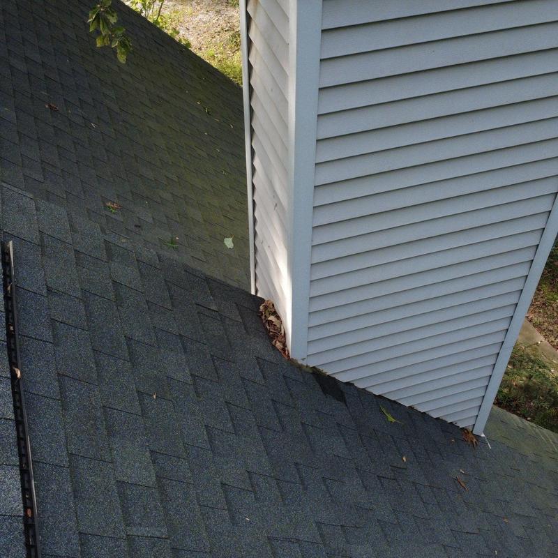 Asphalt shingle roofing near white siding chimney base