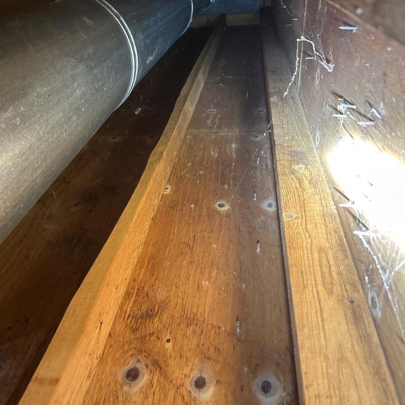 Attic wooden floorboards near ductwork and cobwebs