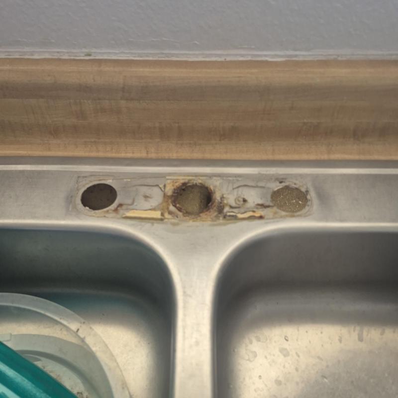 Kitchen sink faucet mounting holes rust damage close-up Kitchen sink faucet mounting holes rust damage close-up