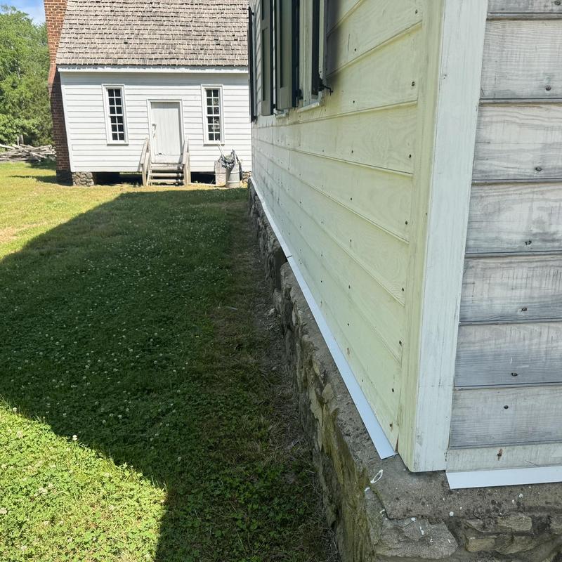 Metal flashing installation on historic foundation stone wall