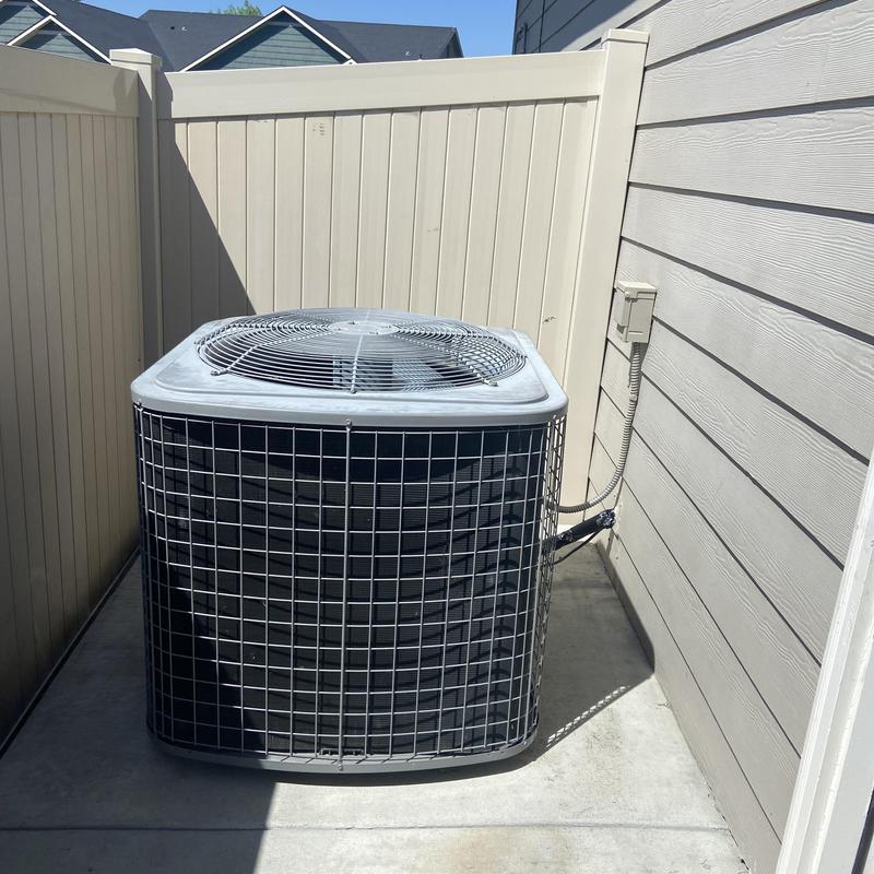 Air conditioning condenser unit beside house wall