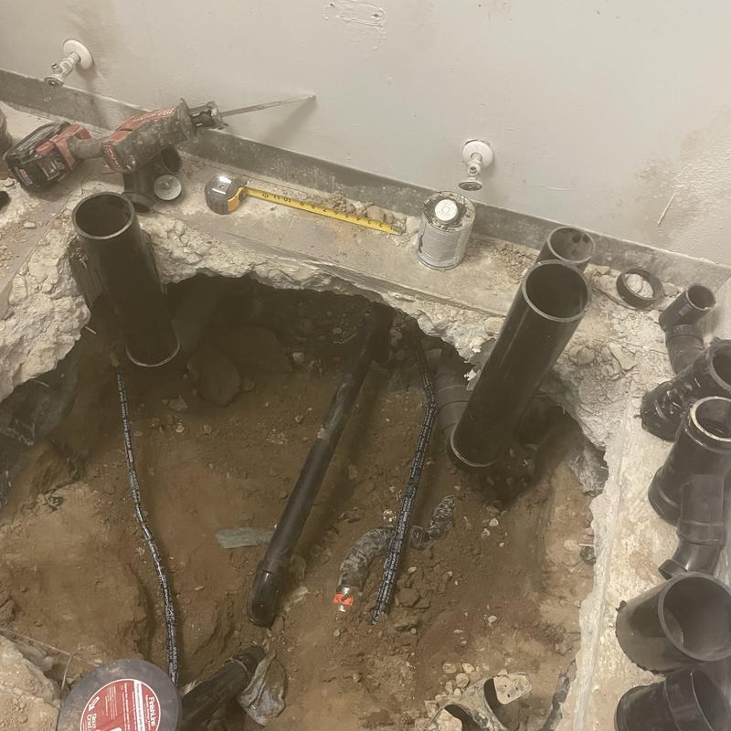 Bathroom drain pipes excavation with black PVC and tools