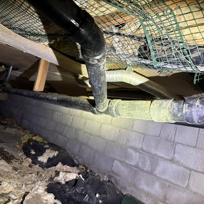 PVC drainage pipes in crawl space with insulation debris PVC drainage pipes in crawl space with insulation debris