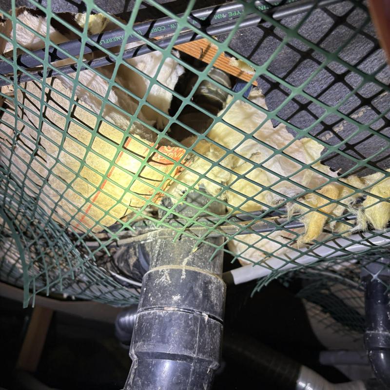 Black drain pipe and insulation behind safety netting Black drain pipe and insulation behind safety netting