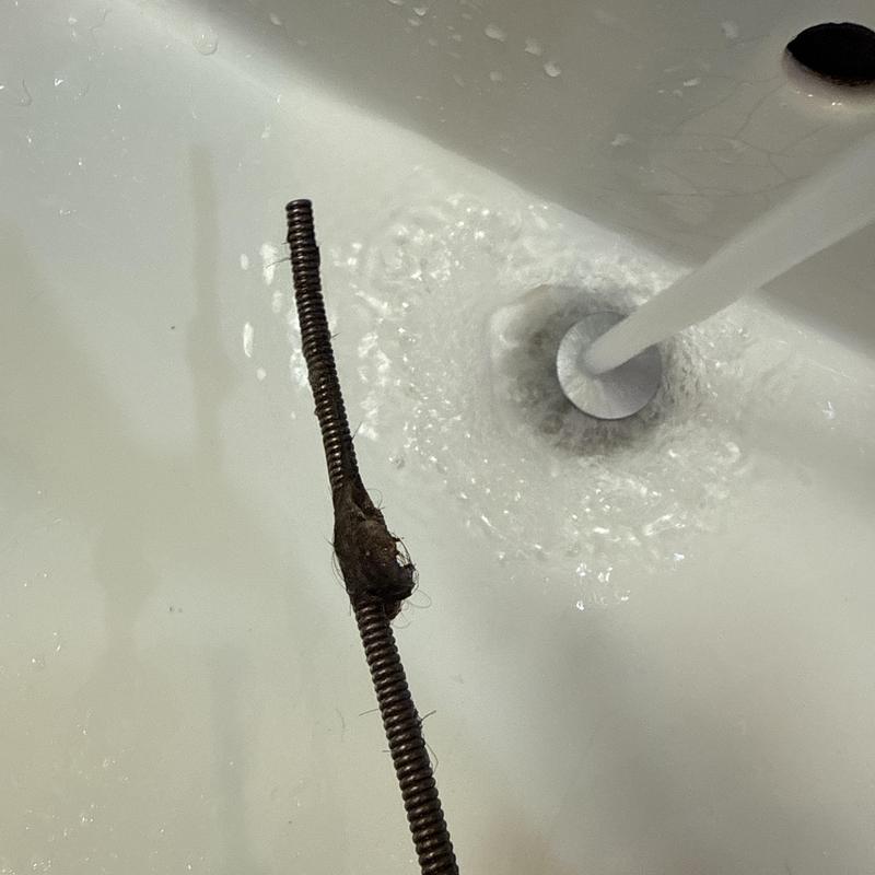 Bathroom sink drain with cleared hair clog and running water Bathroom sink drain with cleared hair clog and running water