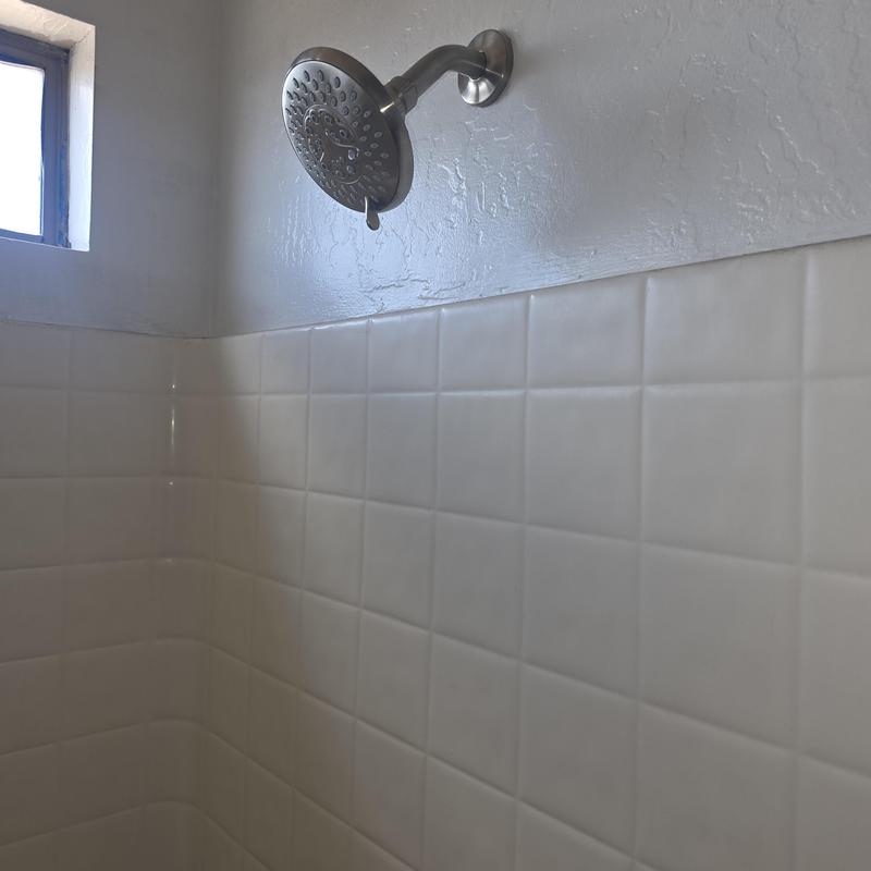 Shower head and tiled shower wall in bathroom