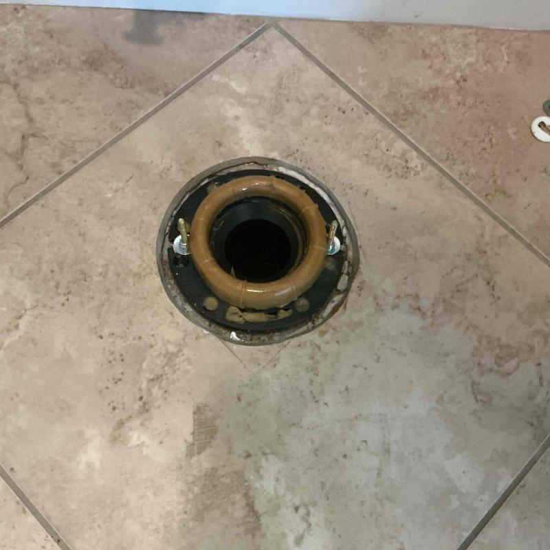 Toilet flange with new wax ring on tile floor