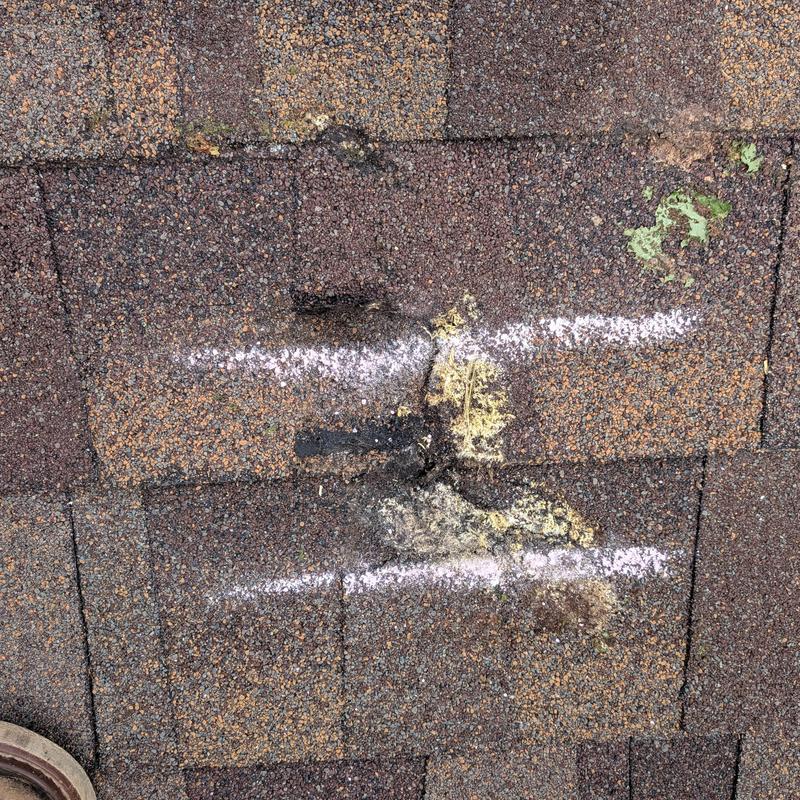 Asphalt roof shingles with damage marked for repair Asphalt roof shingles with damage marked for repair