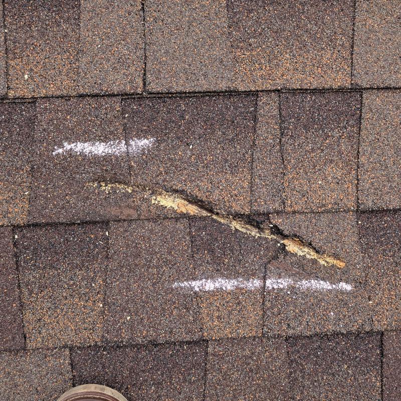 Asphalt roof shingles with damage marked for repair Asphalt roof shingles with damage marked for repair