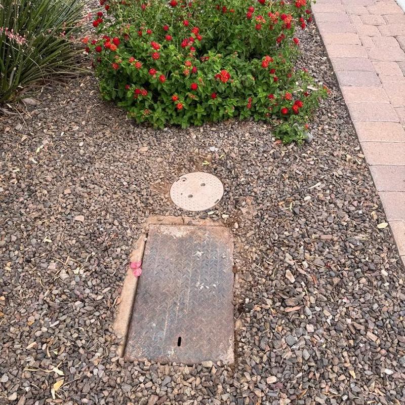 Water main cover surrounded by landscaping rocks and flowers