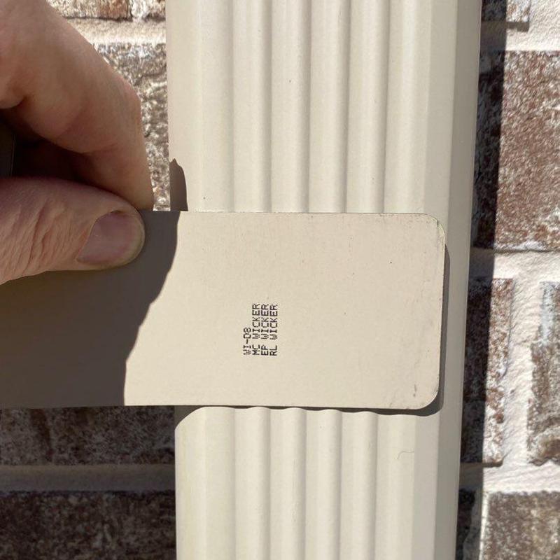 Gutter downspout color matching test near brick wall