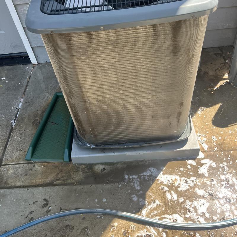 Outdoor AC unit coil with cleaning soap and hose