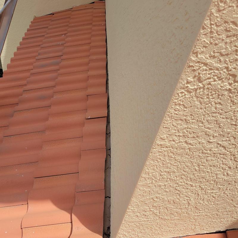 Concrete tile roof with cracked and slipped tiles near wall