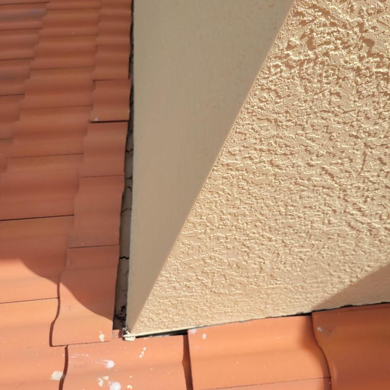Concrete tile roof with slipped and cracked tiles near chimney