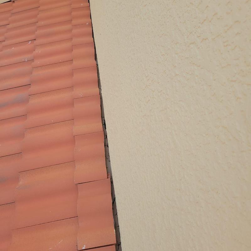 Concrete tile roof with slipped and cracked tiles near wall