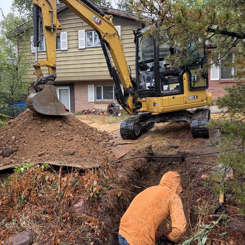 Sewer excavation with backhoe in residential yard