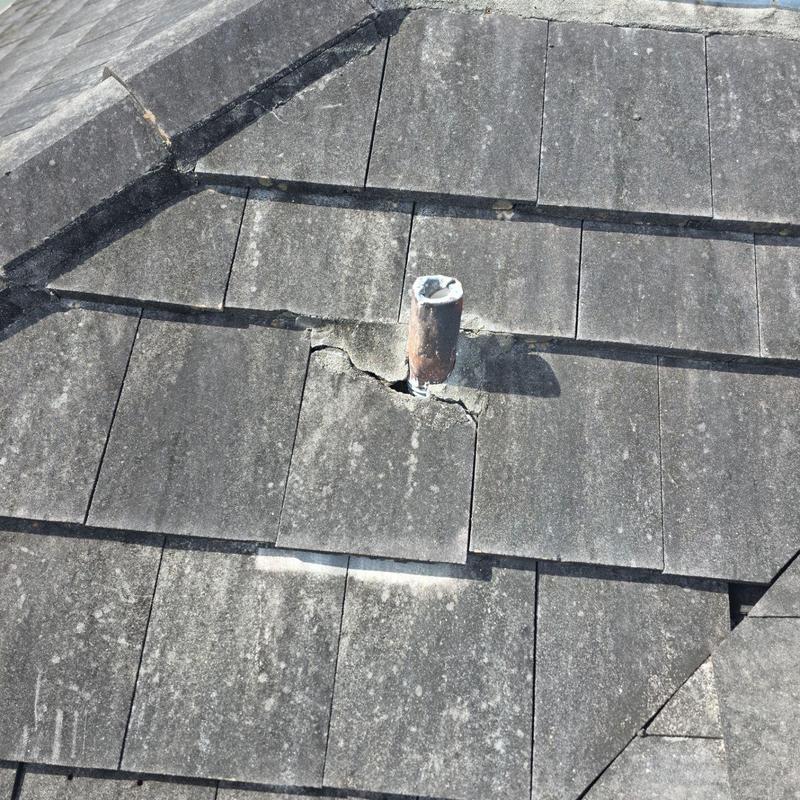 Concrete tile roof with broken tiles around pipe flashing