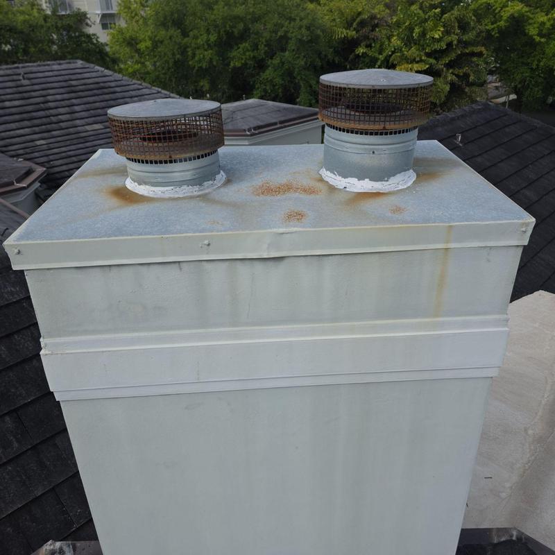 Metal chimney cap with rust spots and vents