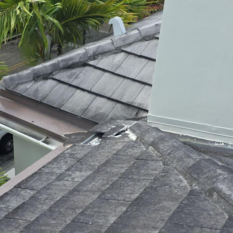 Concrete tile roof with broken tile near chimney