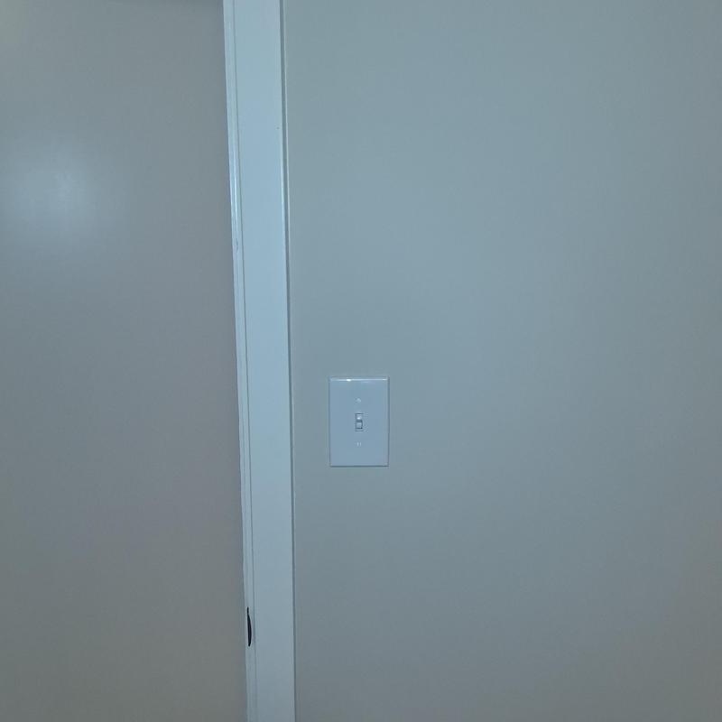 Light switch with white cover plate on gray wall