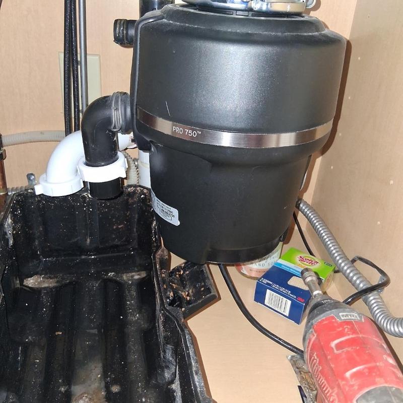 Garbage disposal unit cleaning with power tool under sink
