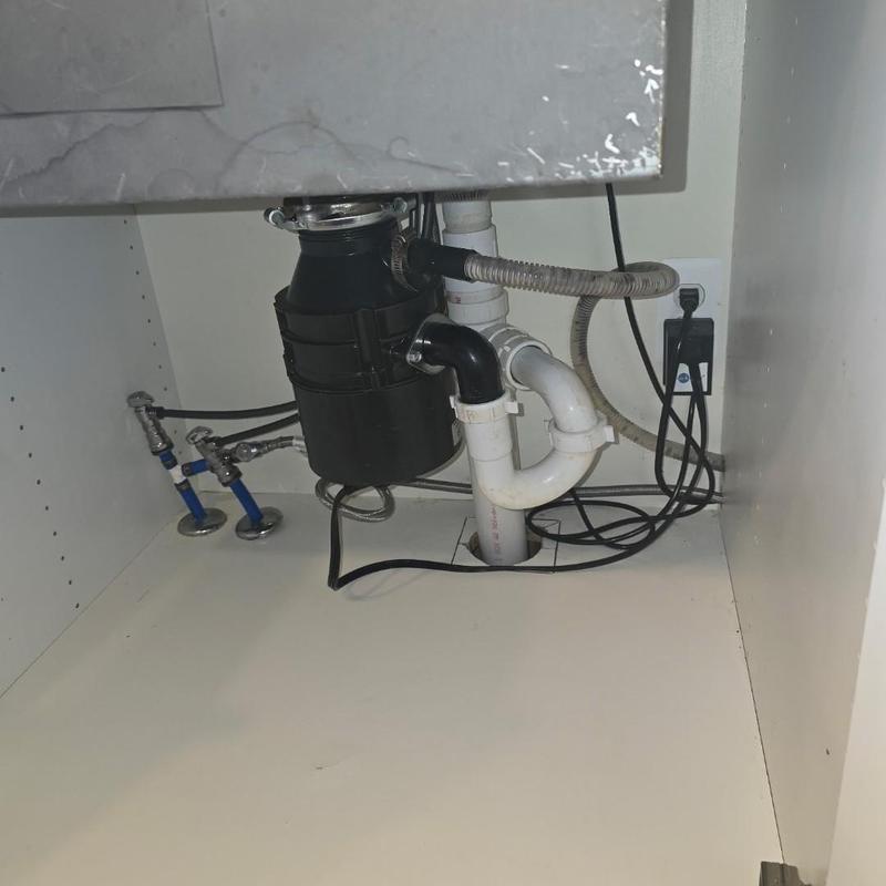 Garbage disposal and kitchen drain pipes under sink
