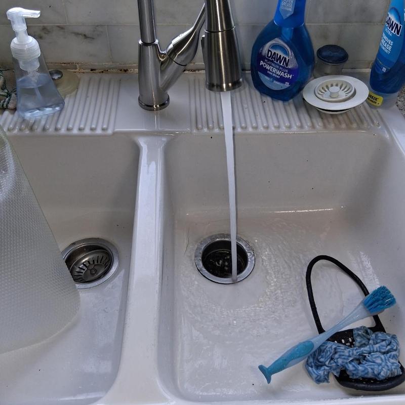 Kitchen faucet with running water over sink basin