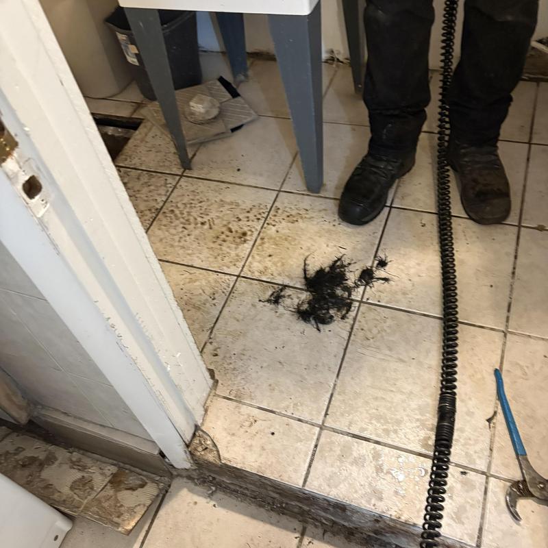 Main line drain cleaning debris on tiled floor Main line drain cleaning debris on tiled floor