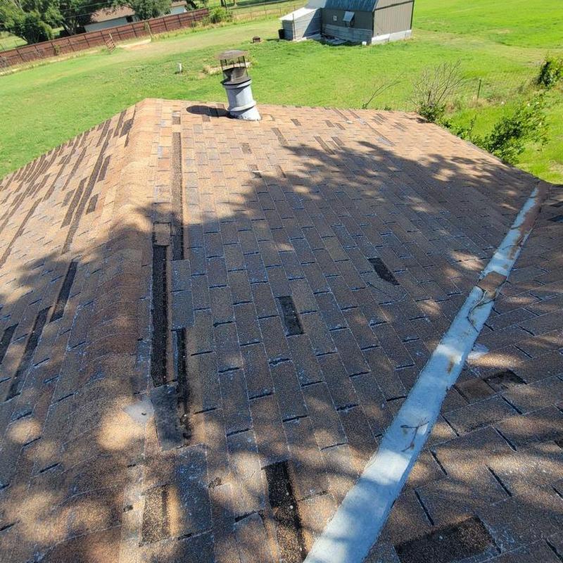 Asphalt shingle roof with missing shingles and vent pipe