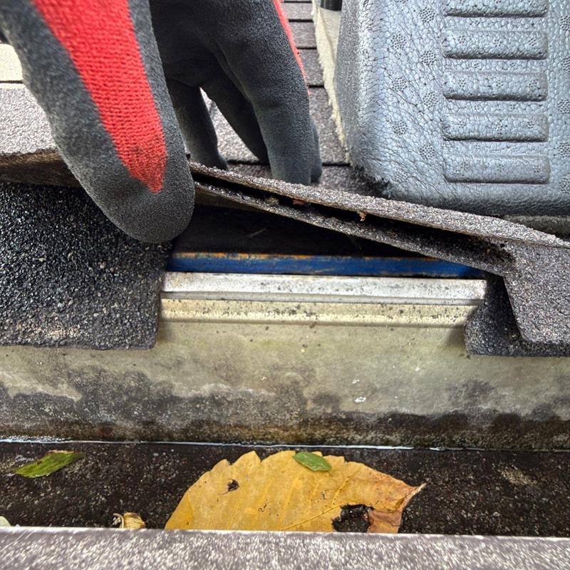 Roof shingles lifted revealing weather barrier and metal flashing