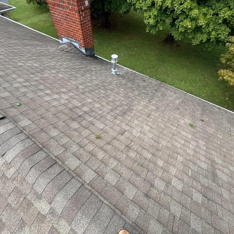 Asphalt shingle roof with hail damage near chimney